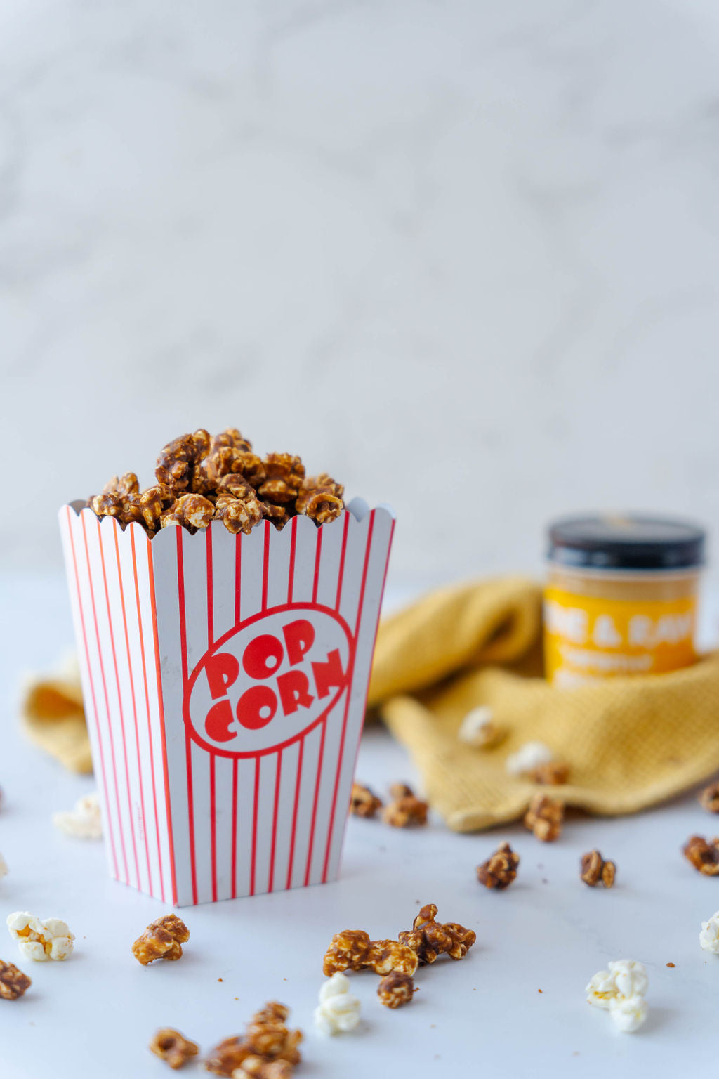 caramel popcorn with a jar of caramel gooeyiness in the background