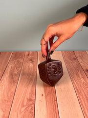 A person holding chocolate dreidel with their hand