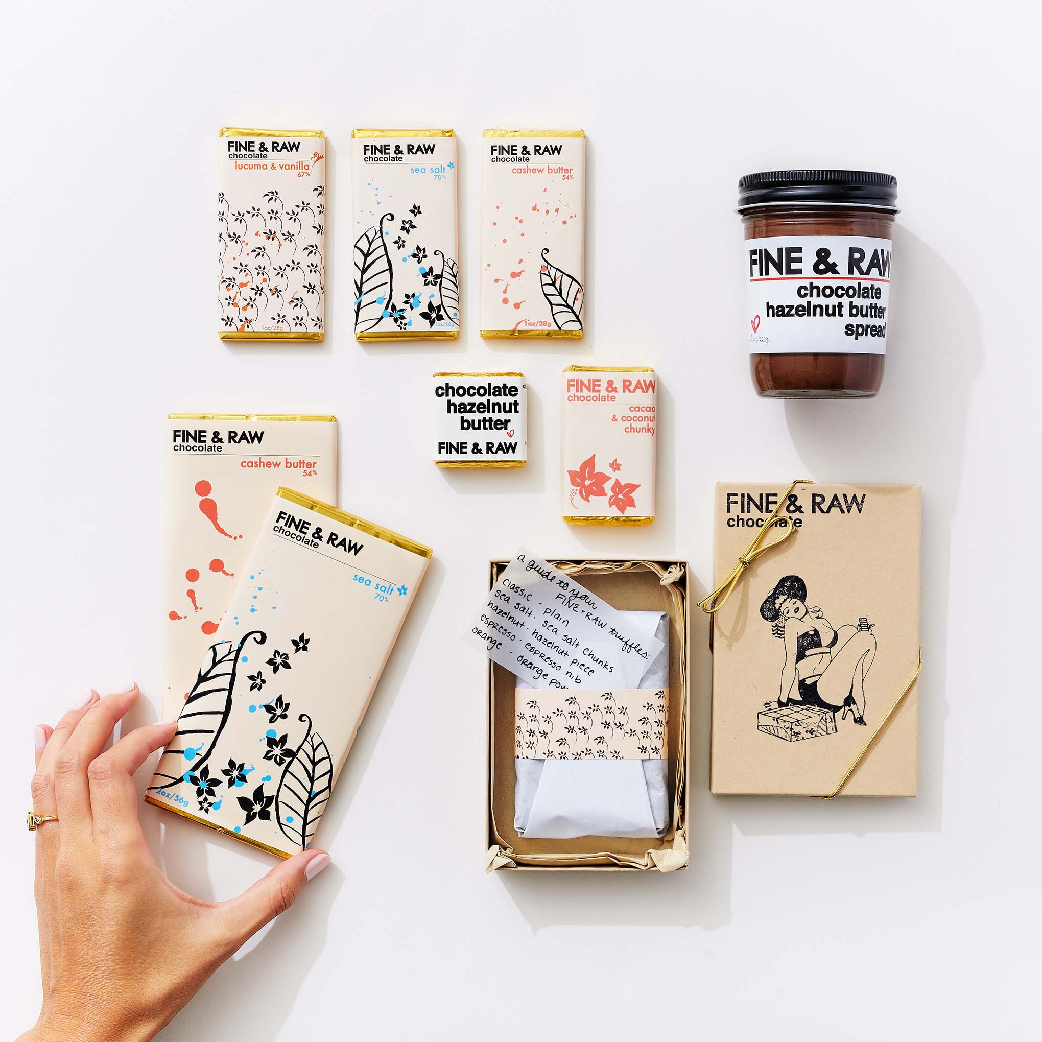 Collection of Fine & Raw chocolate bars and hazelnut butter on a white background