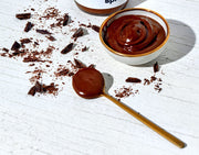 Chocolate Hazelnut Butter Spread in a bowl and in a spoon with chocolate flakes surrounding the bowl and spoon